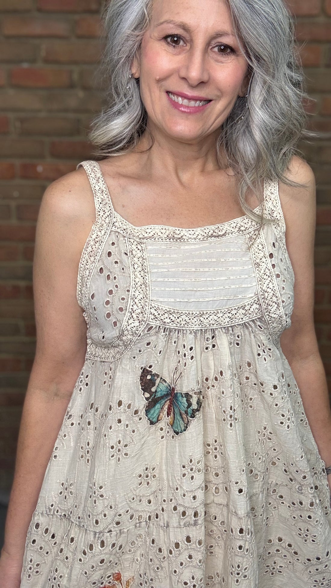 Woman wearing a Eyelet Lace Applique Dress with Serendipity Lace Maxi Skirt against a brick wall