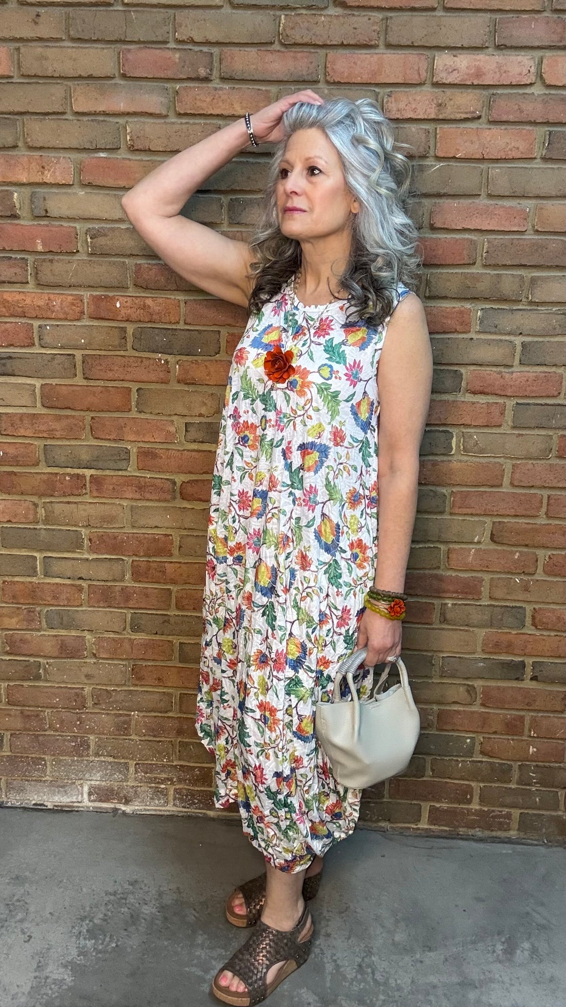 Woman in Bright Floral Crinkle Tank Dress standing against a brick wall
