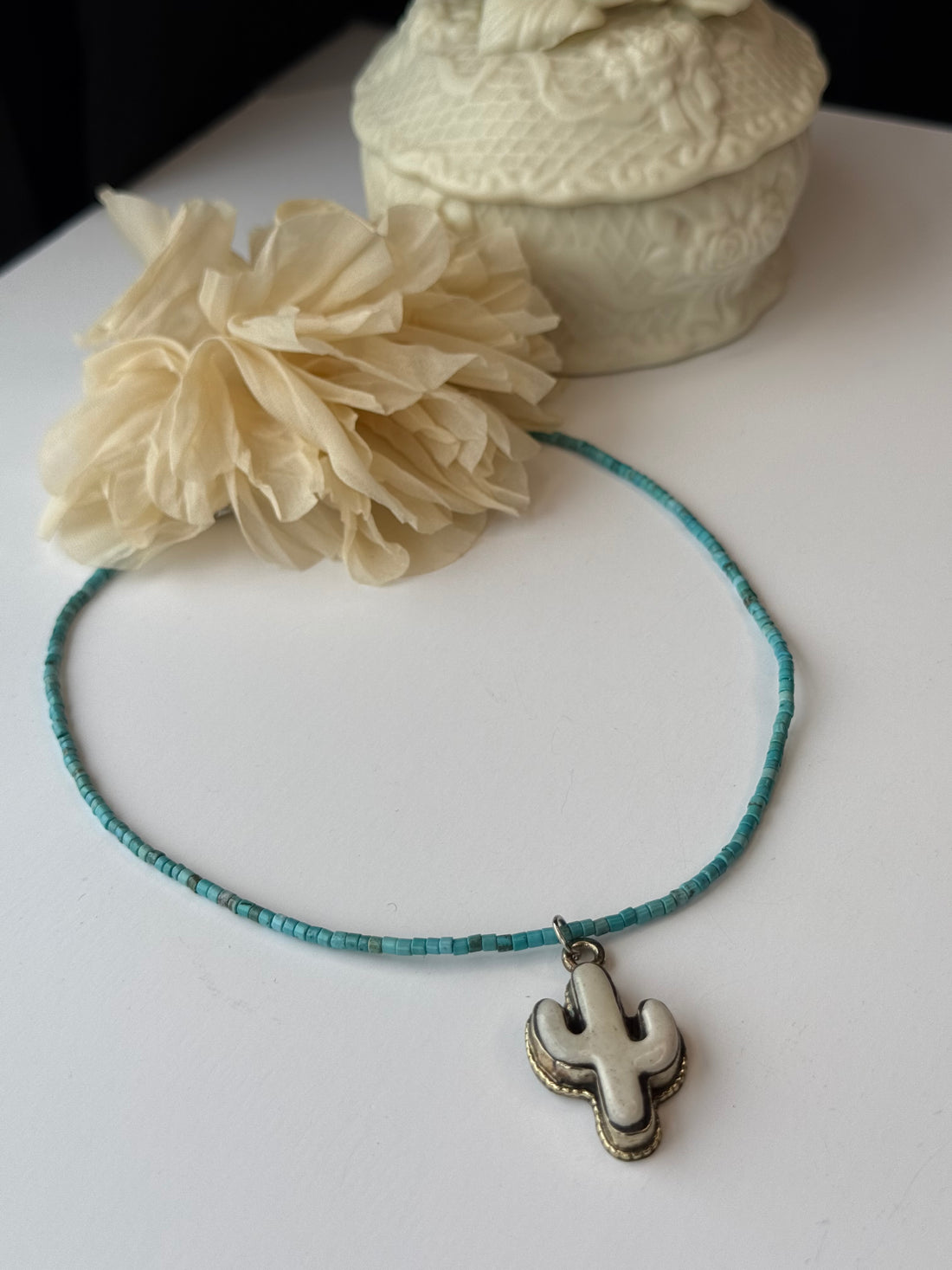 Necklace with a cactus pendant on a white surface