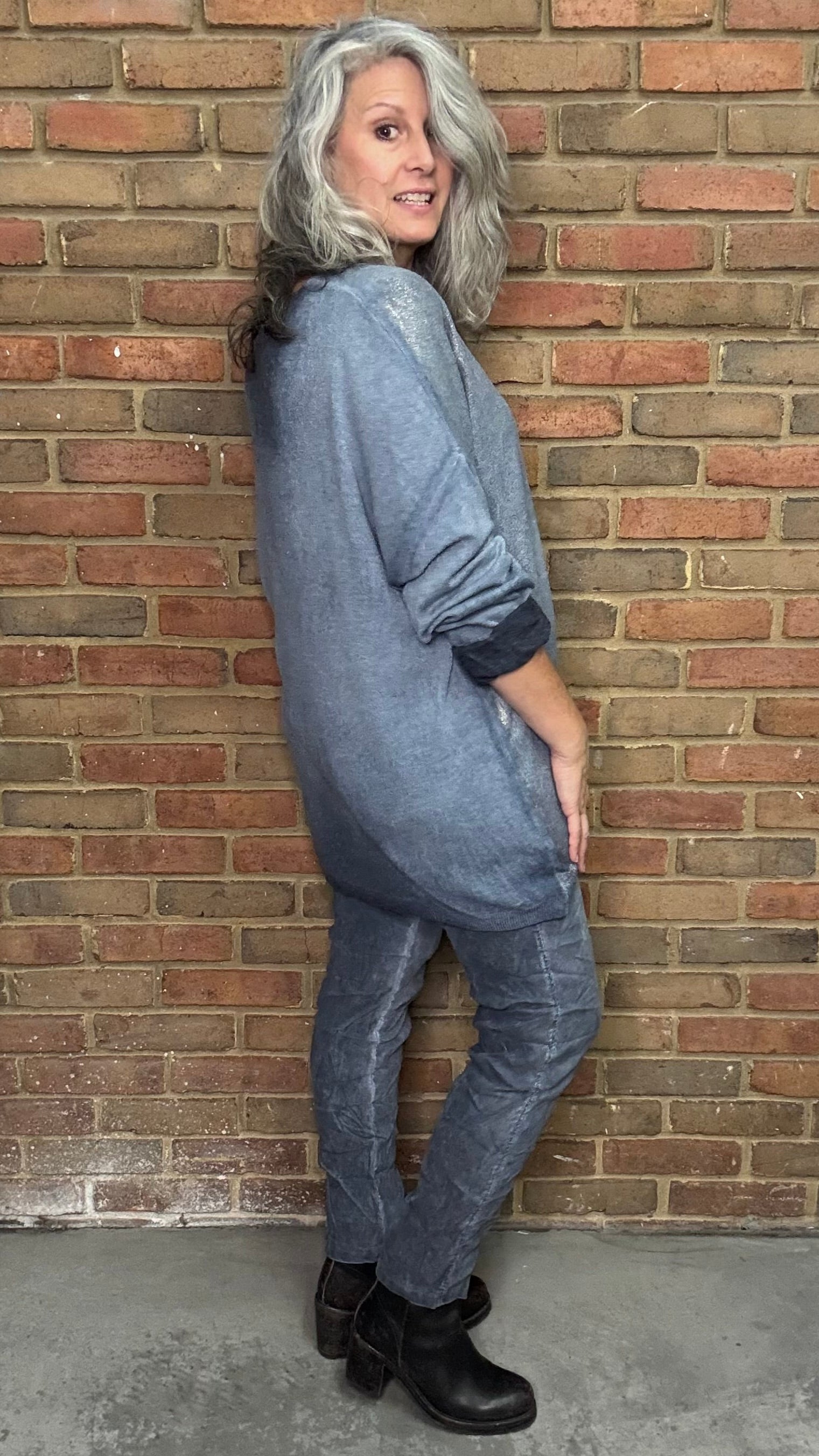 Person wearing a blue outfit standing against a brick wall