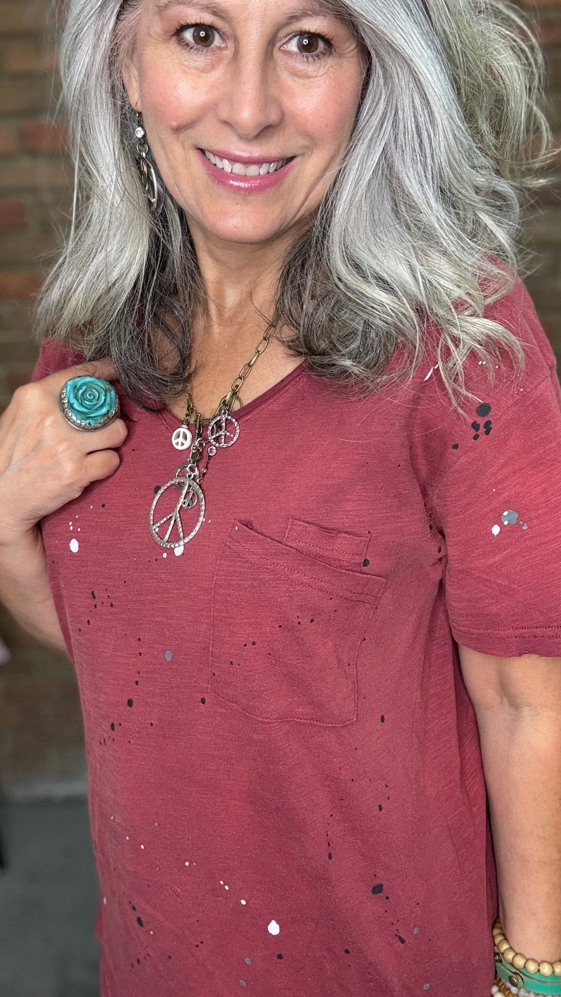 Woman in red shirt in front of brick wall.