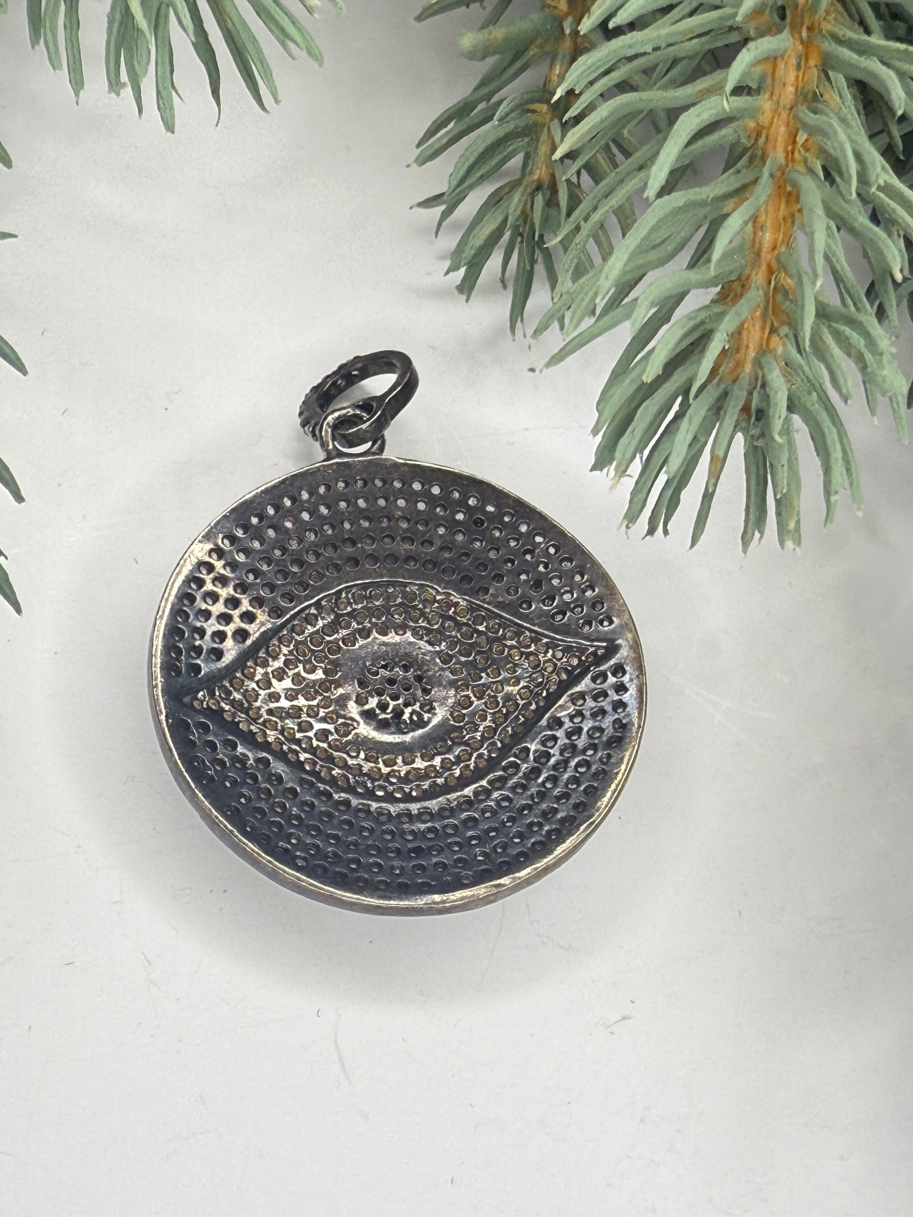 Back of metal pendant on a light background with greenery