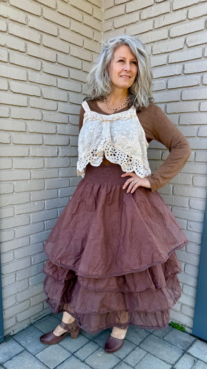Woman in a layered dress standing against a brick wall