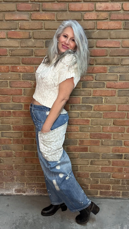 Woman standing in front of a brick wall wearing the Big Pocket Denim Pants and the Oatmeal Sweater Top.