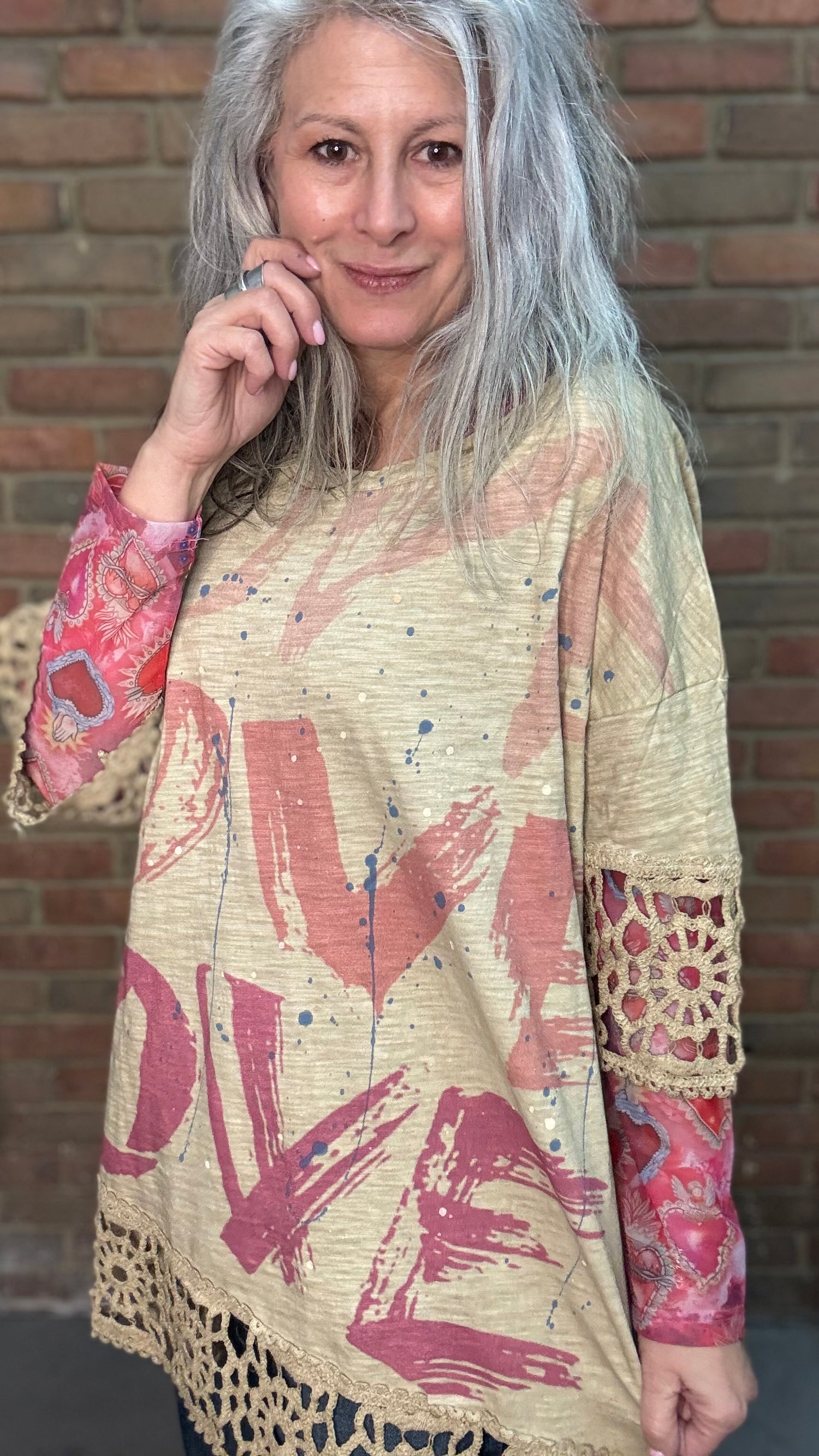 Woman wearing The LOVE top standing against a brick wall.