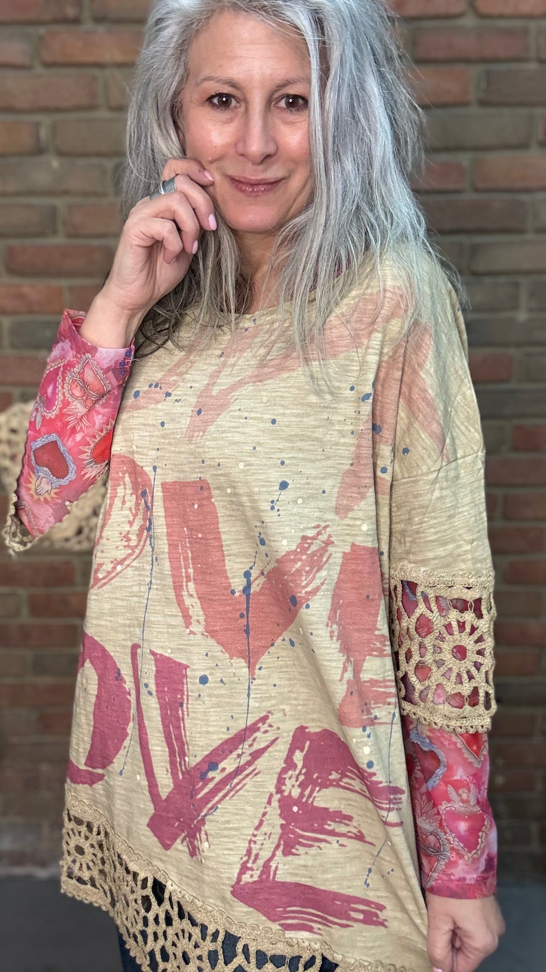 Woman wearing The LOVE top standing against a brick wall.