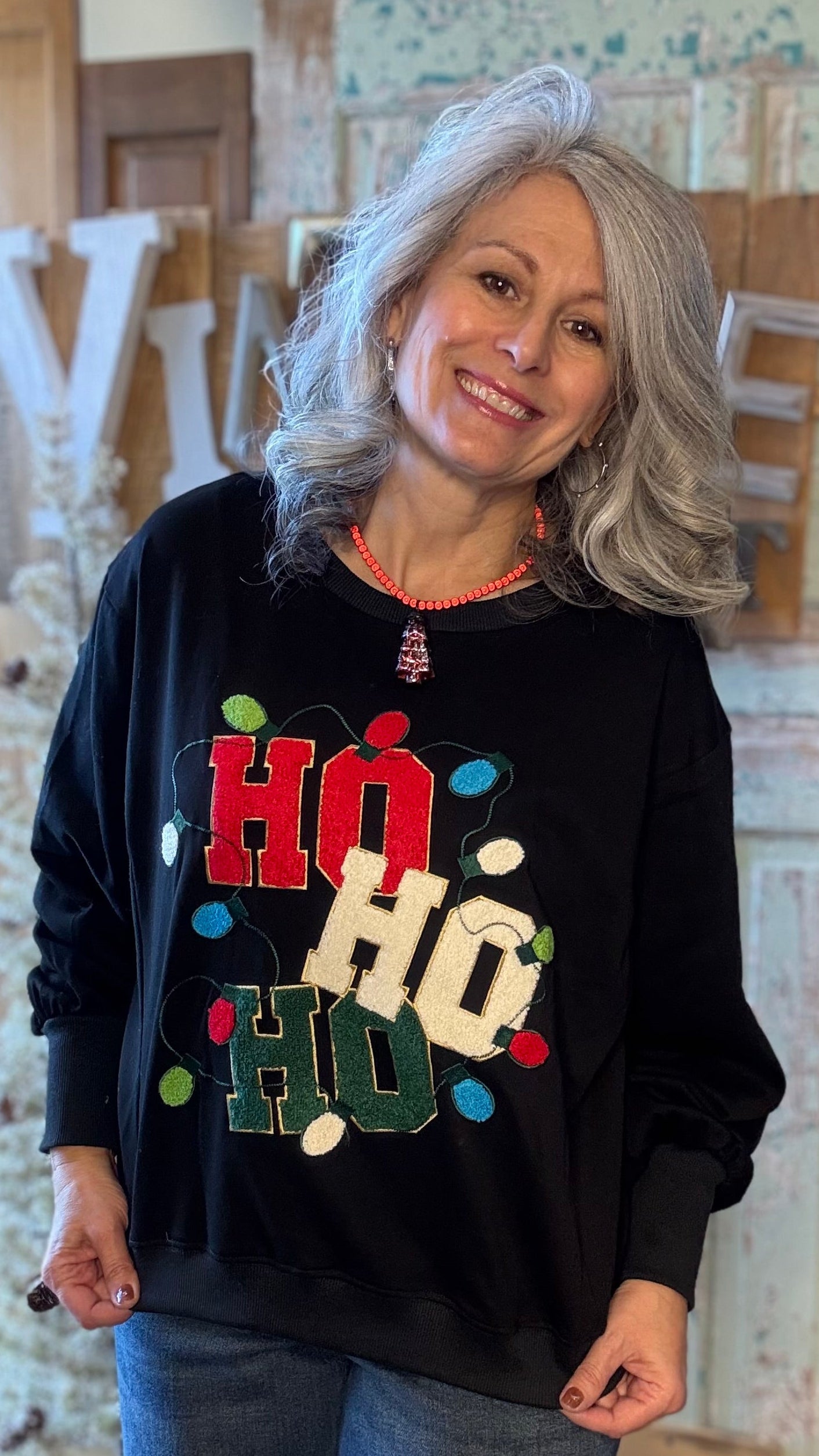 Woman wearing a black sweater with colorful text in a rustic indoor setting