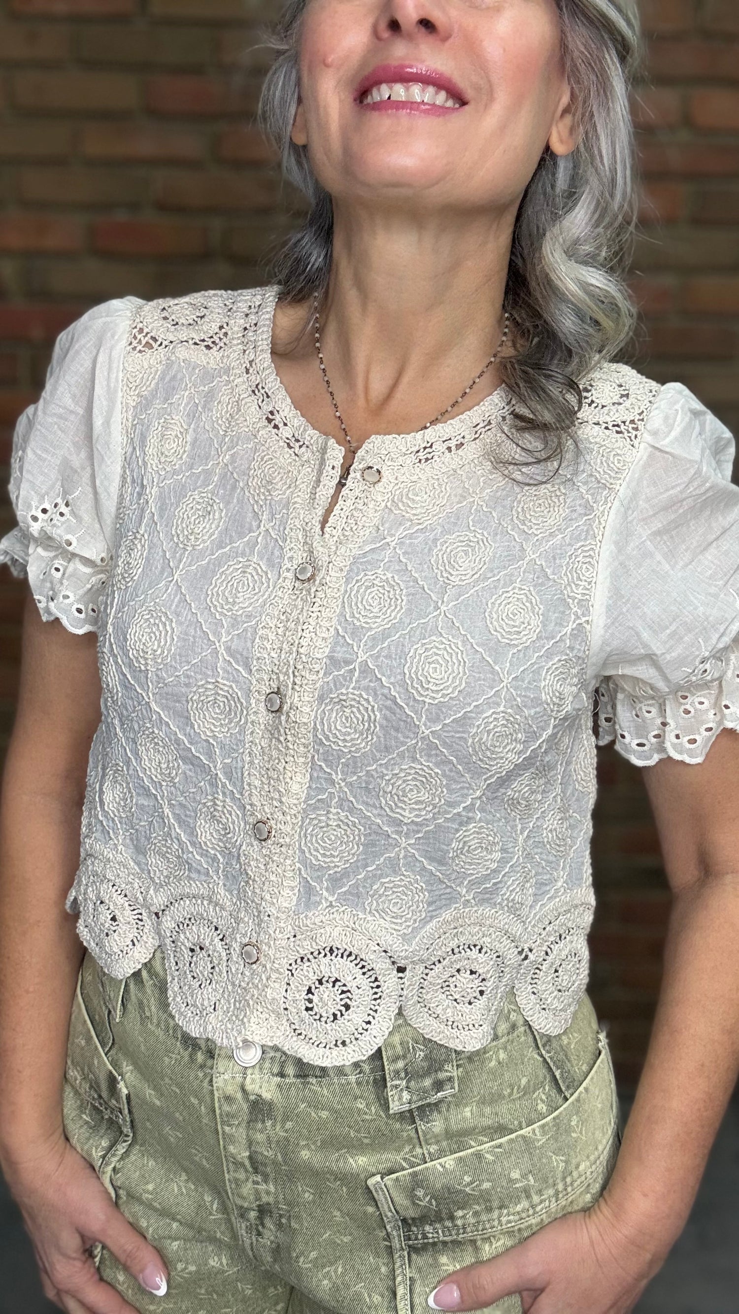 Woman wearing the Crochet Embroidery Button-Up Top and Floral Printed Barrel Pants with a brick wall background