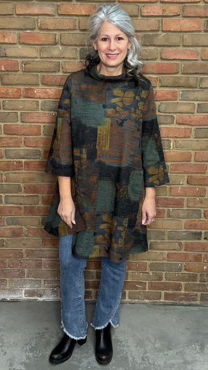 Woman wearing Blythe Tawn Tunic and  the Front Tulip Hem Bootcut Pant jeans standing against a brick wall.