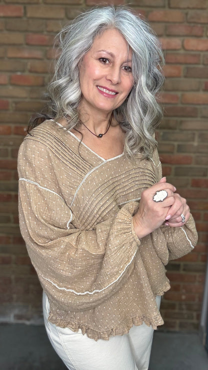 Woman wearing Mocha and Ivory Print Long Sleeve Top and blue jeans standing against a brick wall.