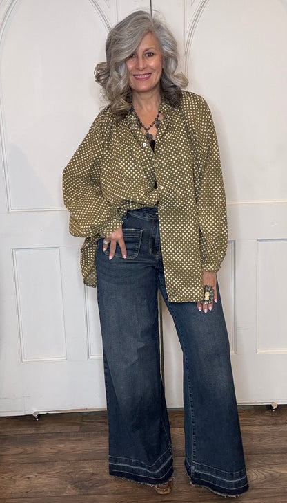 Woman wearing the Sweet Nothings Top-Olive Dot and Judy Blue Palazzo jeans standing against a white paneled wall.