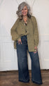 Woman wearing the Sweet Nothings Top-Olive Dot and Judy Blue Palazzo jeans standing against a white paneled wall.