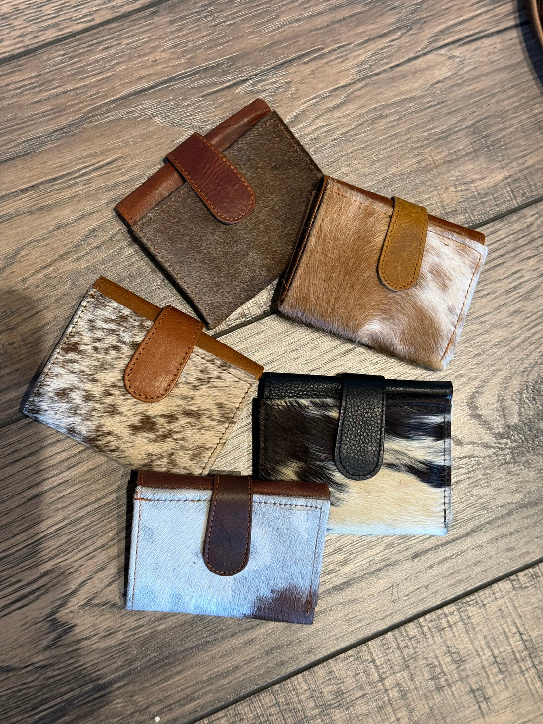 Collection of cowhide leather wallets on a wooden surface