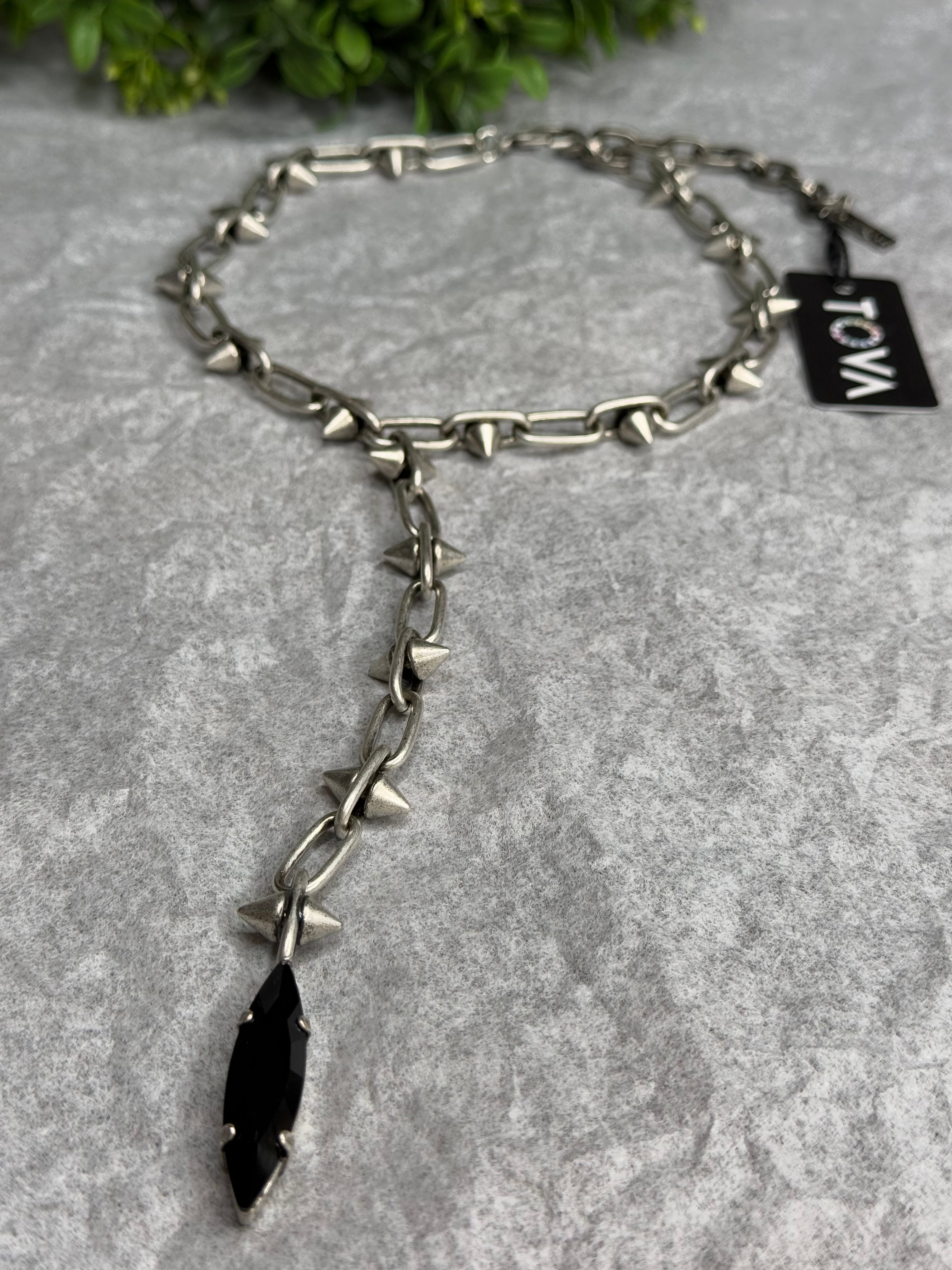 Necklace with spikes and a tag on a textured surface