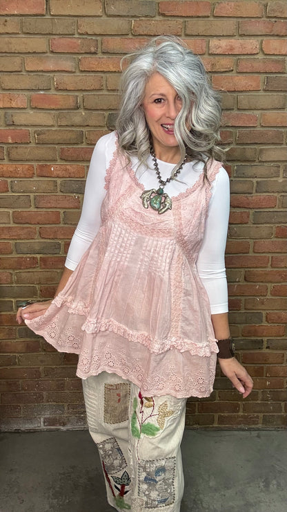 Woman wearing Eyelet Lace Tank over a white shirt, standing against a brick wall.