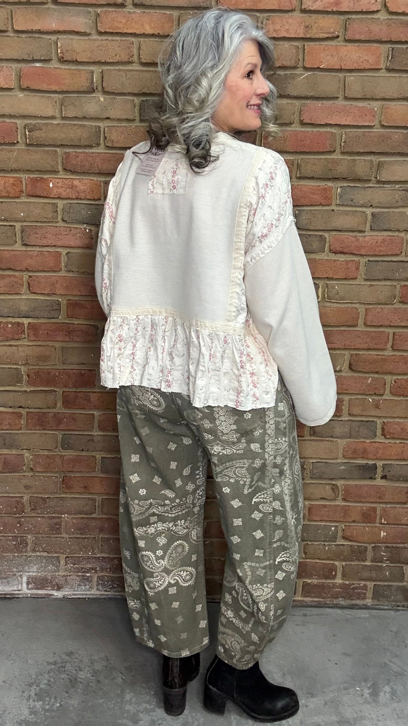 Woman wearing the Natural Flare Sleeve Mix Media Top and Paisley Print Barrel Jean standing against a brick wall.