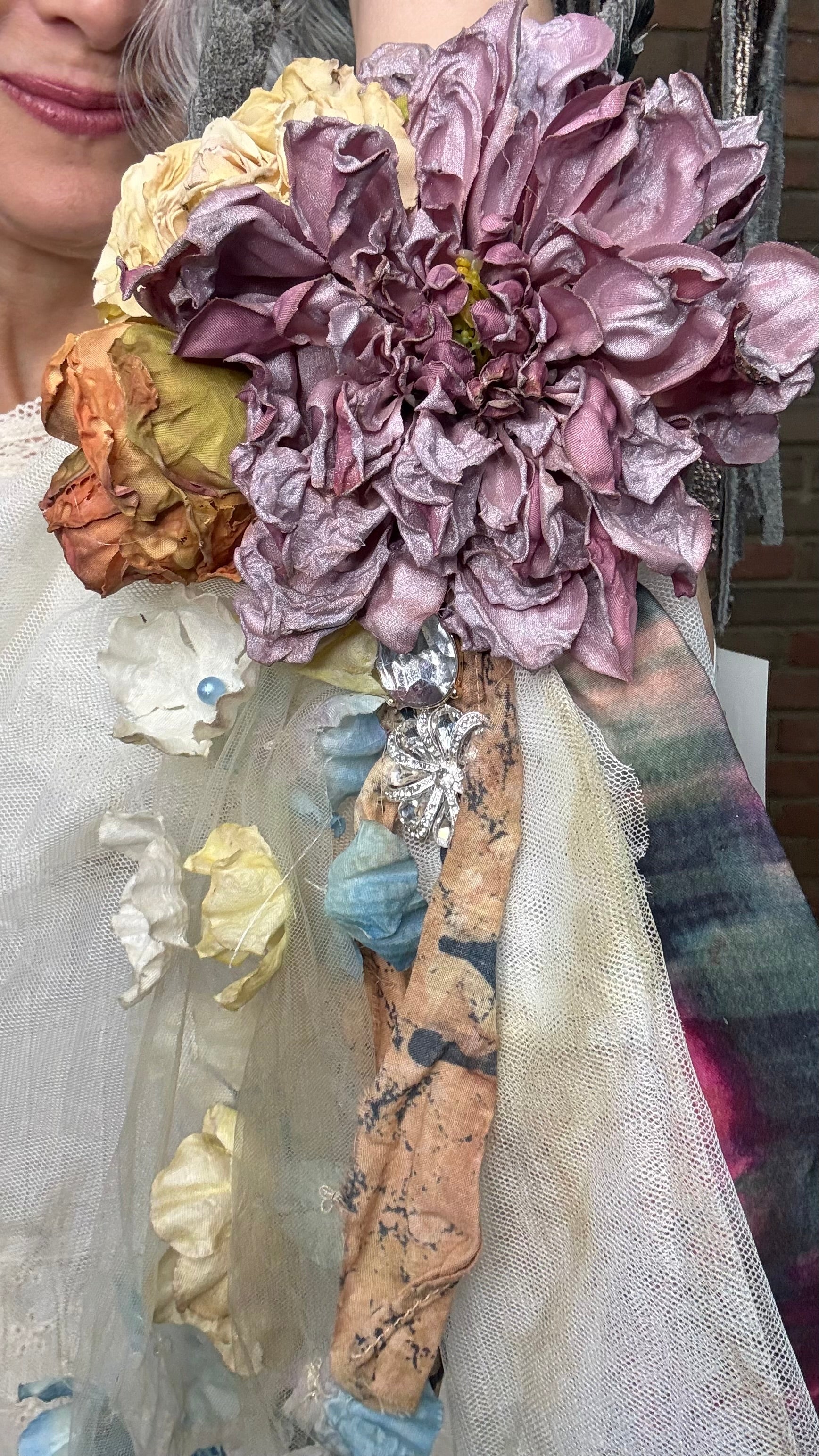 Person wearing a white outfit with Flower Garden Necklace and a cowboy hat against a brick wall.