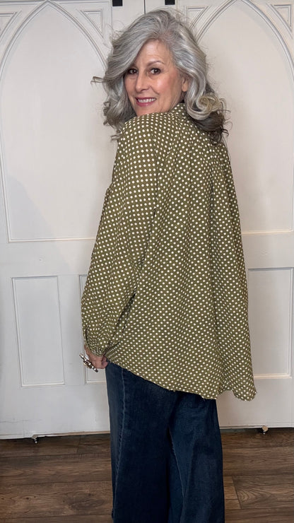 Woman wearing the Sweet Nothings Top-Olive Dot and Judy Blue Palazzo jeans standing against a white paneled wall.