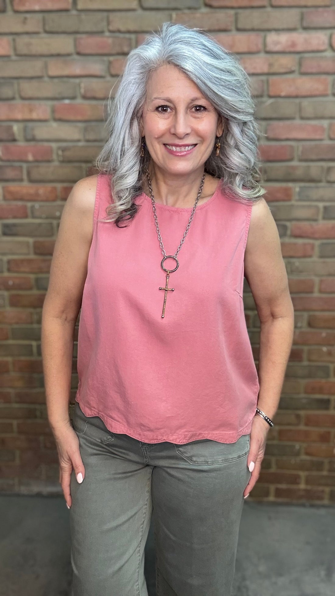 Woman wearing Scallop Hem Button Detail Top with sage pants against a brick wall