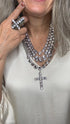 Close-up of a person wearing a decorative necklace with a cross pendant.