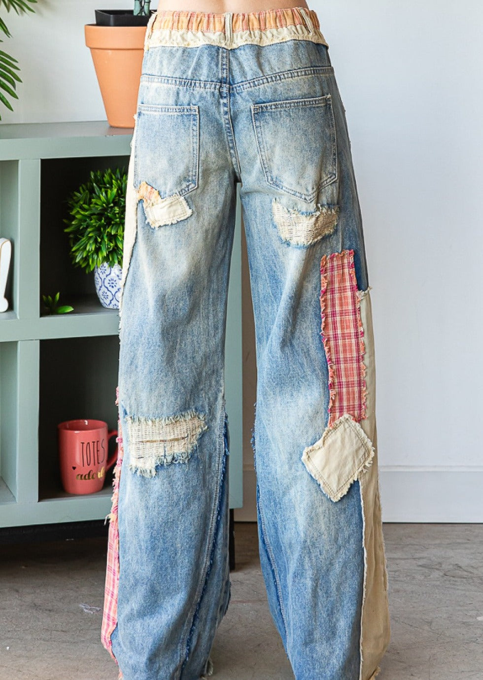 close up back view of patch detail wide straight denim pants on a model.