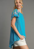 Side view of Linen Round Neck Hi-Lo Hem Embroidery Top on a model.
