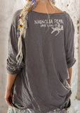 Back view of model wearing Neil Young Viggo T-shirt in color Ozzy.  Graphic on T-shirt of Magnolia Pearl cupid logo.