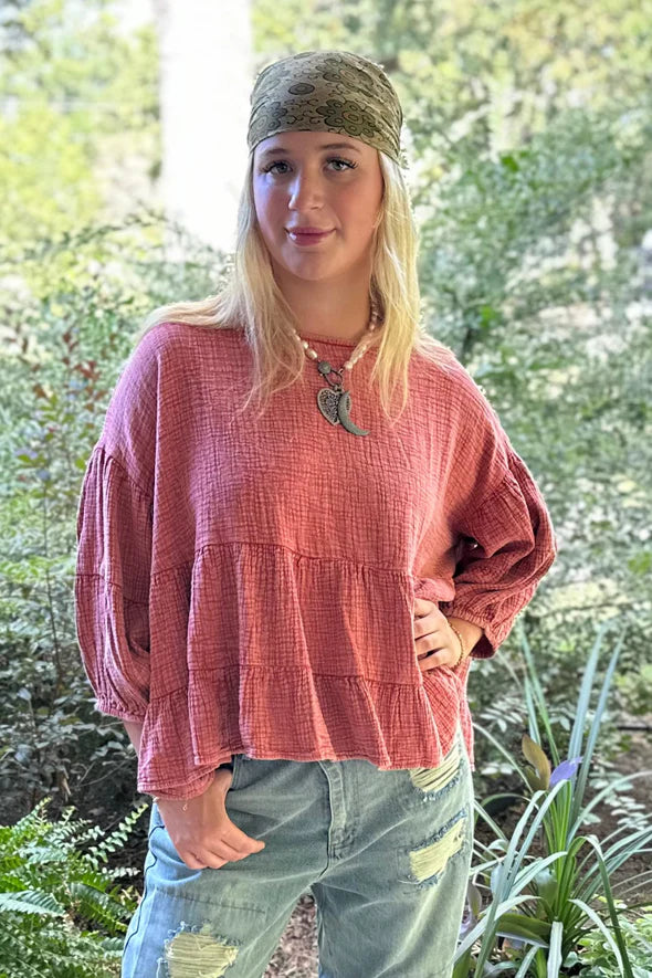 Person wearing a pink top and green pants standing in a natural setting