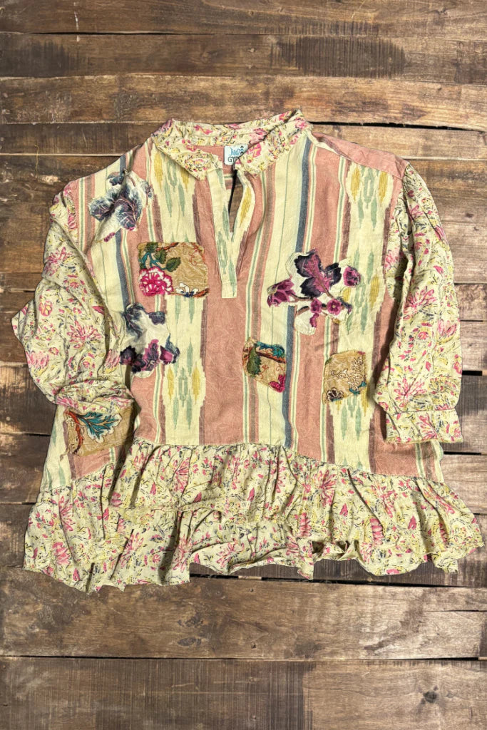 Floral and striped blouse with ruffled details on a wooden background