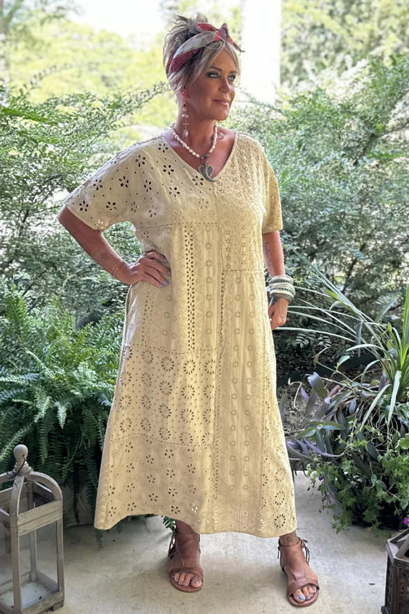 Woman wearing a yellow lace dress standing in a garden.
