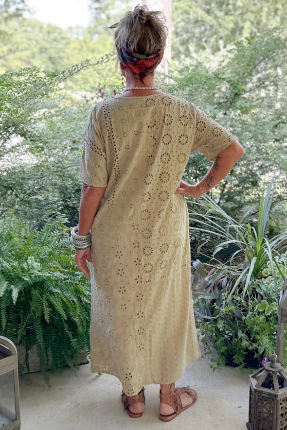 Woman in a beige patterned dress standing in a garden