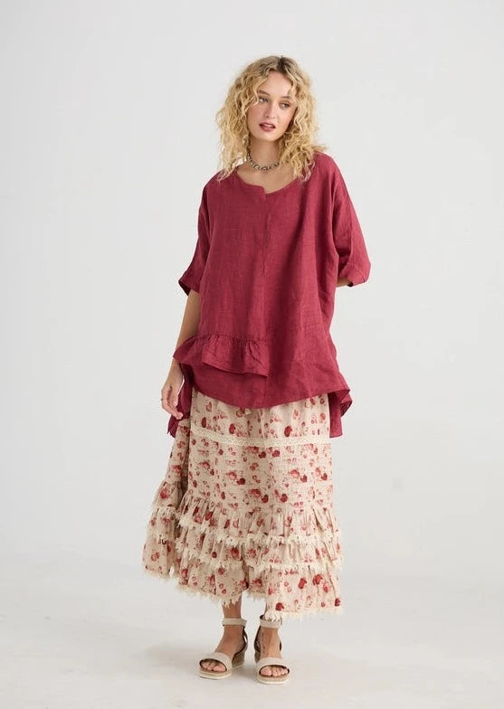 front view of Perdita Cotton Skirt in Dark Rose on a model wearing a long red colored shirt.