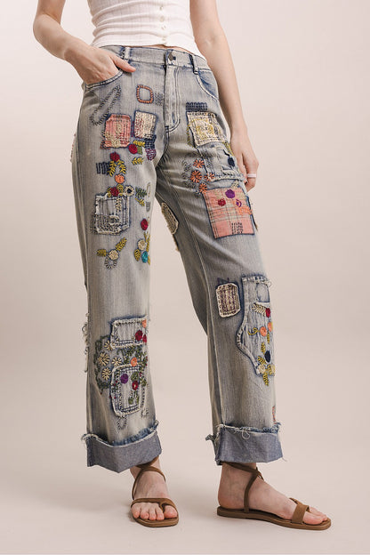Person wearing jeans with colorful patches on a plain background