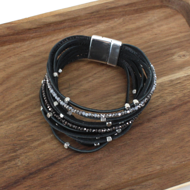 Multi-layered black leather bracelet with beads on a wooden surface