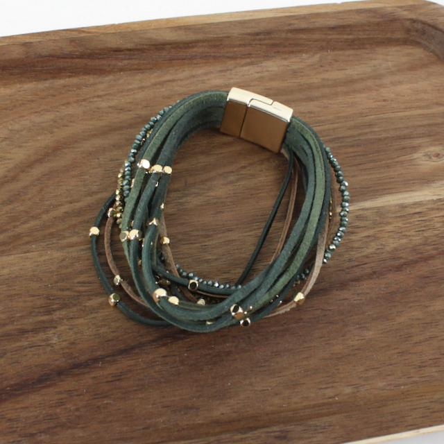 Green multi-strand bracelet with gold accents on a wooden surface