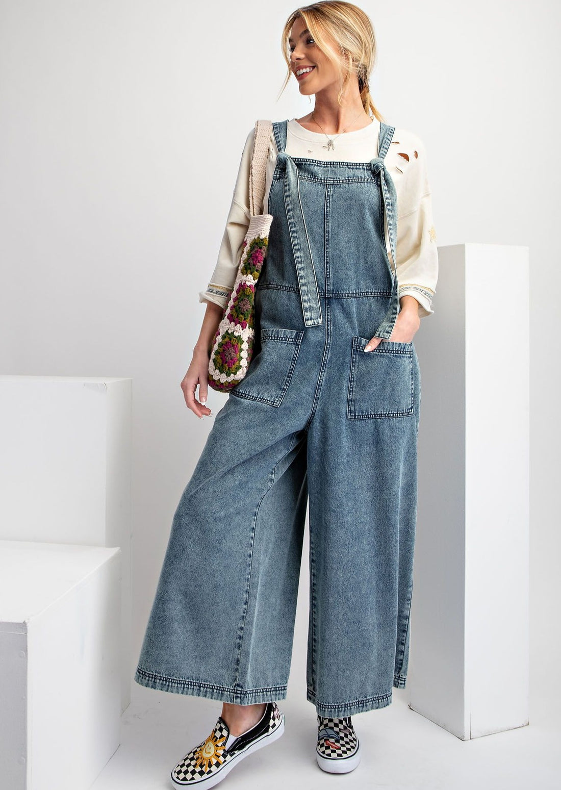 Front view of model wearing wide leg stone washed denim jumpsuit.