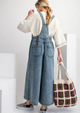 Back view of wide leg stone washed denim jumpsuit on model.