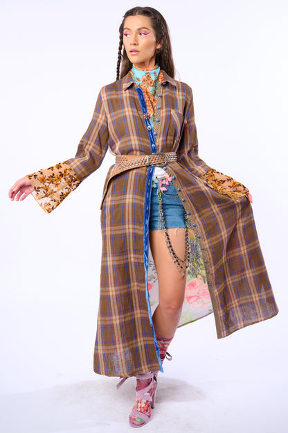 Model wearing a plaid duster with floral patterns and denim shorts on a white background
