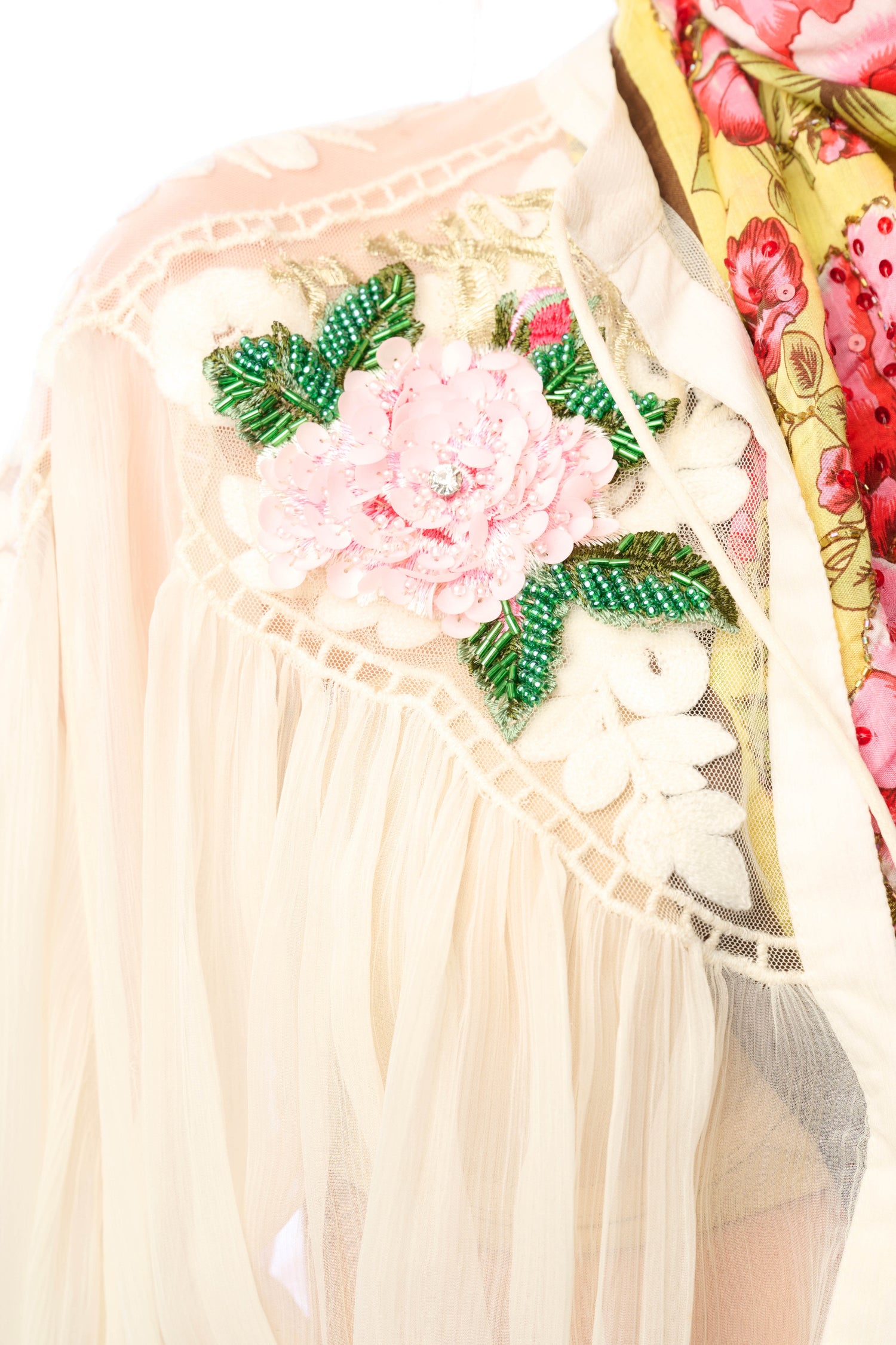 Decorative sequin applique with floral embroidery and beads on a plain background